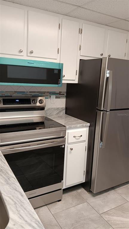 A kitchen features white cabinets, stainless steel appliances, and a marble-patterned countertop — 8402 111TH STREET UNIT 203, SEMINOLE, FL