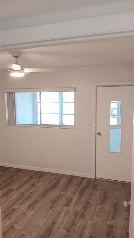A room with light wood-look flooring, a ceiling fan, a window, and a white door — 8402 111TH STREET UNIT 203, SEMINOLE, FL