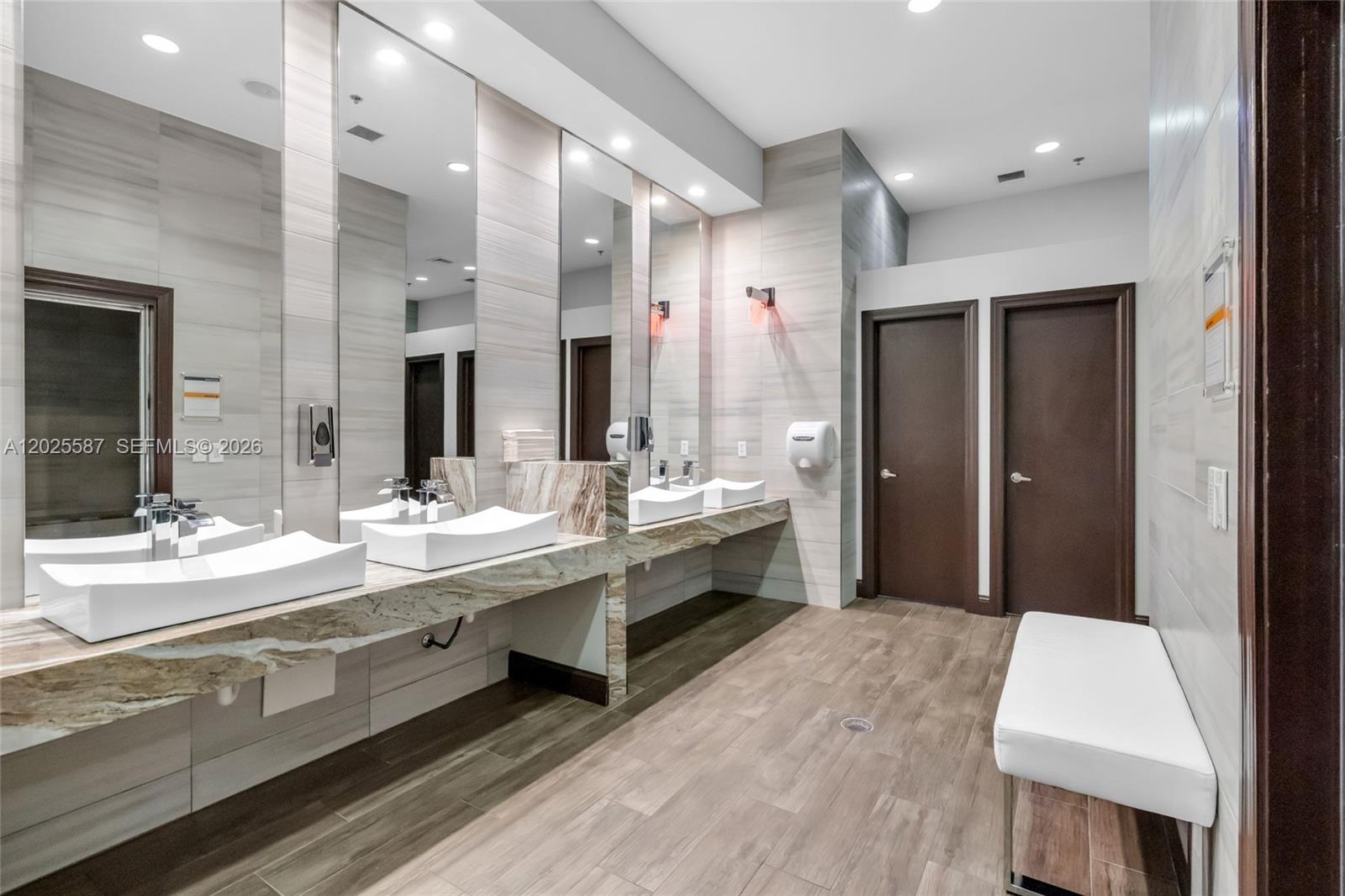 A modern public restroom features dual vessel sinks, marble countertops, and two dark wooden doors — 19508 SW 79th Ct, Cutler Bay FL 33157, CUTLER BAY, FL