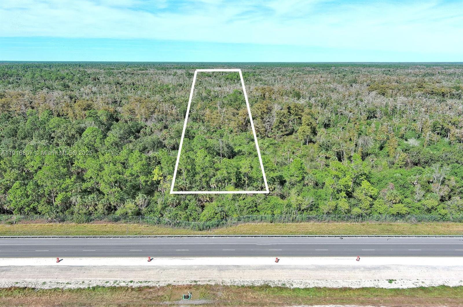 An aerial view shows a trapezoidal plot of land outlined in white bordering a highway — 0 Alligator Alley, Naples FL 34117, NAPLES, FL