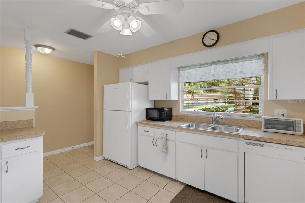 A kitchen features white cabinets, a refrigerator, a double sink, and a ceiling fan — 4574 MOHICAN UNIT 151, SARASOTA, FL