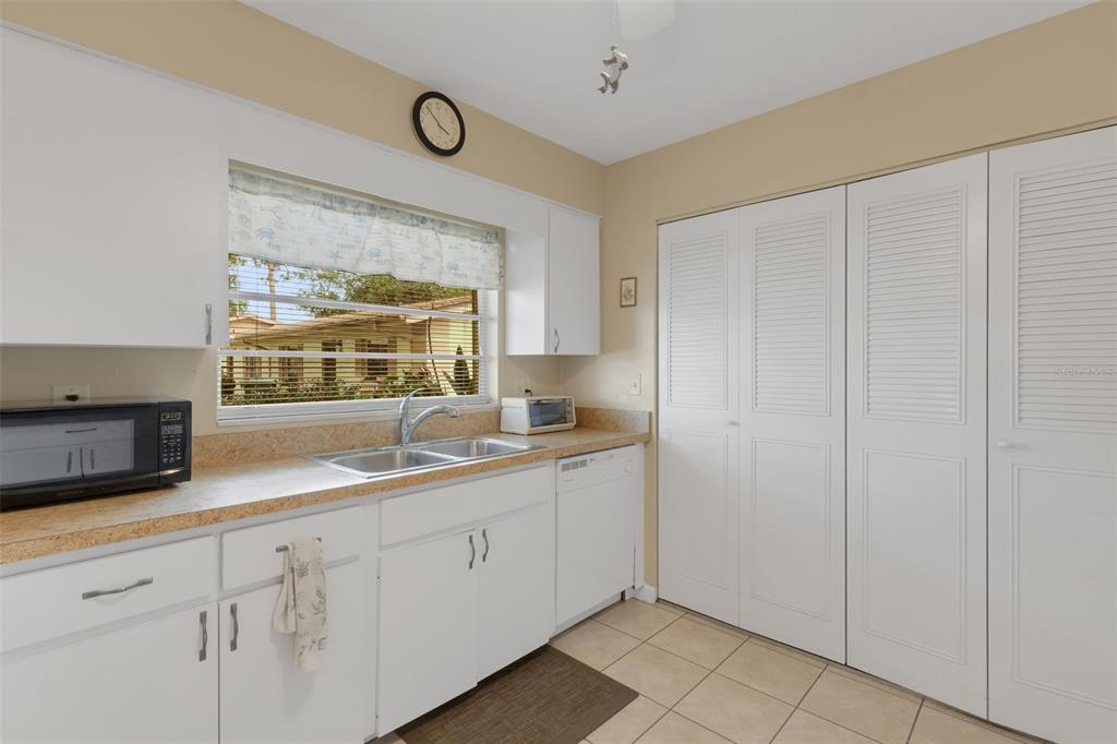 A kitchen features white cabinets, a double sink, a dishwasher, and white louvered closet doors — 4574 MOHICAN UNIT 151, SARASOTA, FL