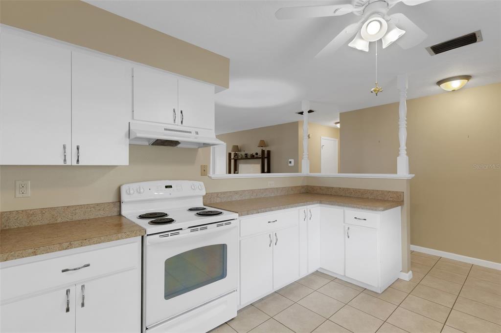 A kitchen with white cabinets, a white electric range, and tan laminate countertops — 4574 MOHICAN UNIT 151, SARASOTA, FL