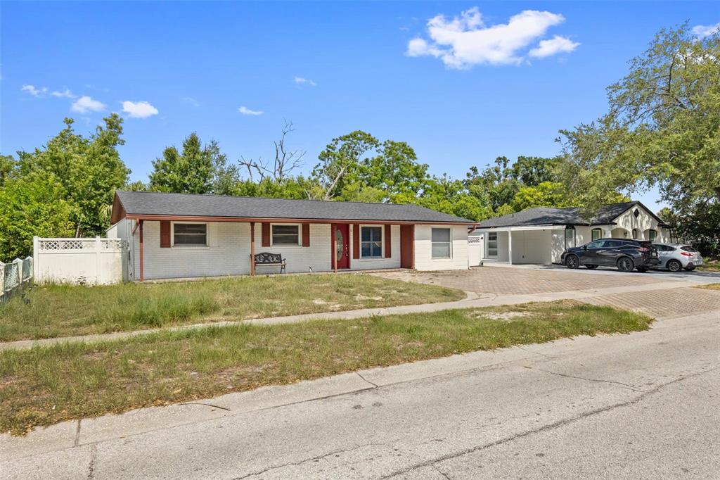 A single-story white brick house with a red door and an attached carport — 5923 YORKSHIRE ROAD, TAMPA, FL