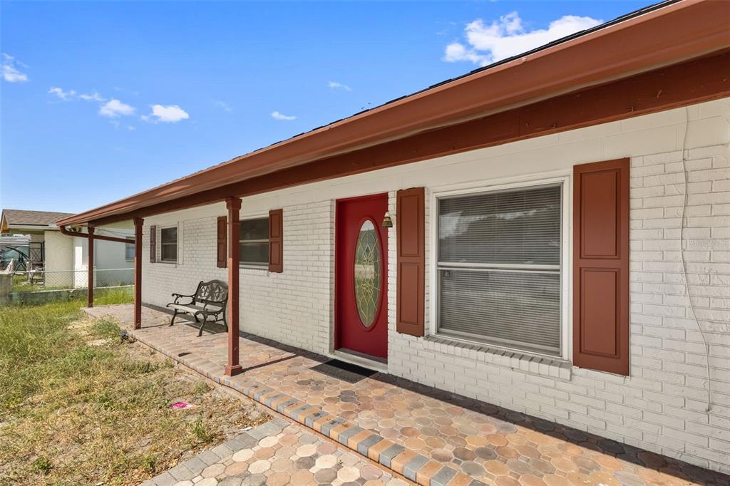 A white brick house exterior features a red front door, brown shutters, and a porch — 5923 YORKSHIRE ROAD, TAMPA, FL