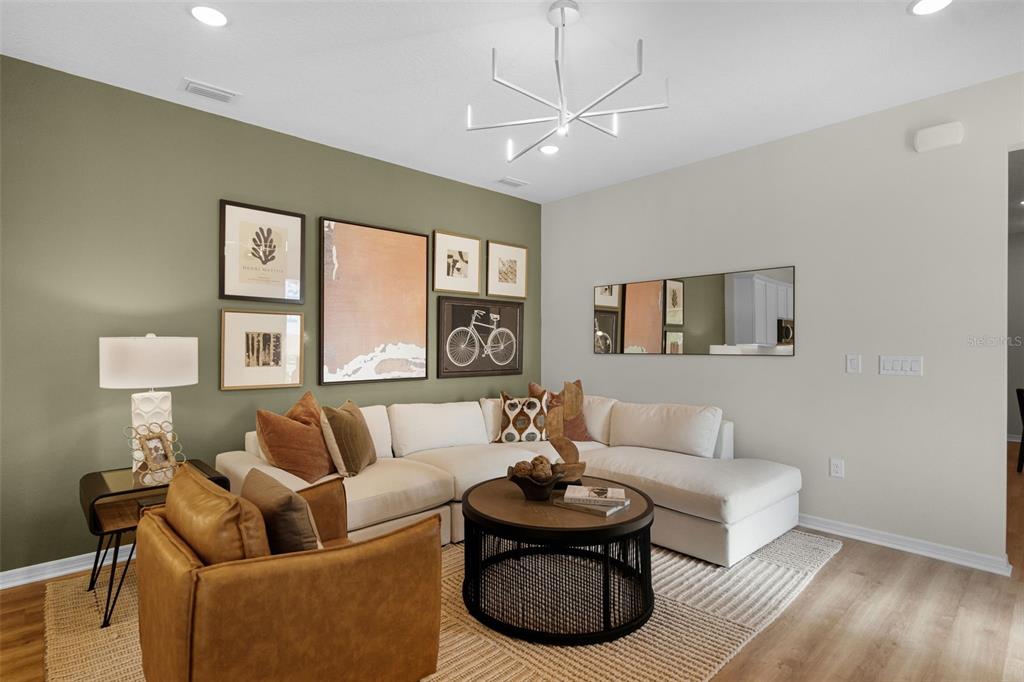 A living room features a white sectional sofa, a round coffee table, and a gallery wall — 1124 CYPRESS ELM DRIVE, DELAND, FL