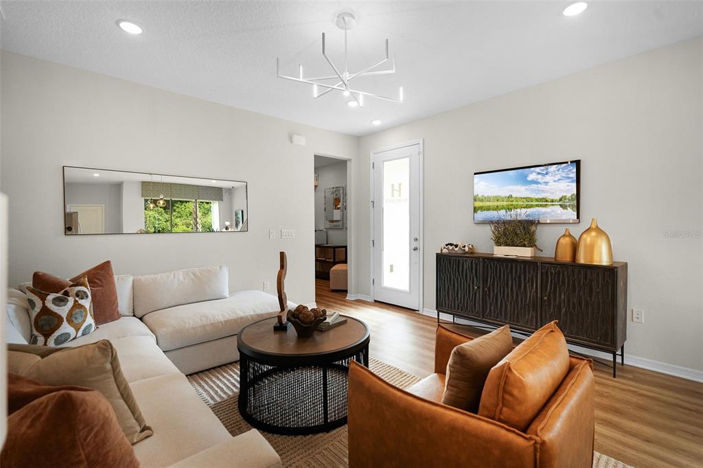 A living room features a white sectional sofa, a round coffee table, and a leather armchair — 1124 CYPRESS ELM DRIVE, DELAND, FL