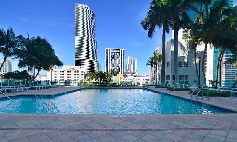 A swimming pool is surrounded by a tiled deck with palm trees and city skyscrapers — 31 SE 5TH STREET UNIT 305, MIAMI, FL