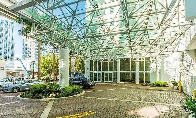 A modern building entrance features a large glass canopy over a circular brick driveway — 31 SE 5TH STREET UNIT 305, MIAMI, FL