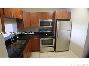 A kitchen features wood cabinets, black countertops, stainless steel appliances, and a double sink — 496 NW 165th St Rd # D112, Miami FL 33169, MIAMI, FL