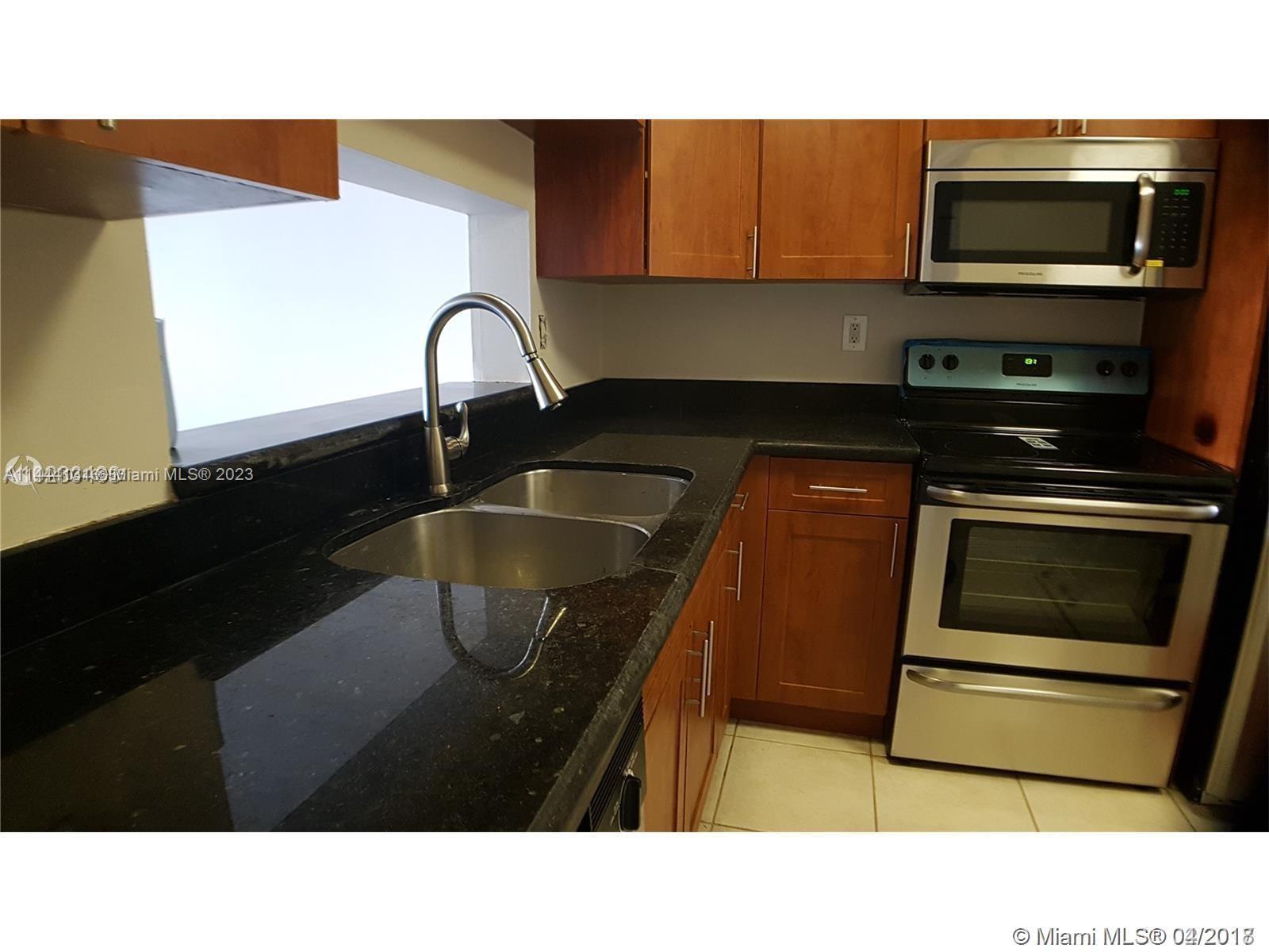 A kitchen features wood cabinets, black granite countertops, stainless steel appliances, and a double sink — 496 NW 165th St Rd # D112, Miami FL 33169, MIAMI, FL