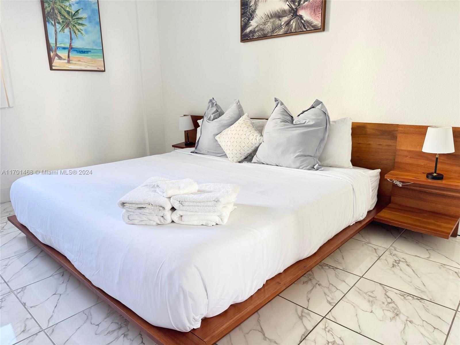 A bedroom features a platform bed with white linens, wooden headboard, and marble tile flooring — 3901 S Ocean Dr # 3Y, Hollywood FL 33019, HOLLYWOOD, FL