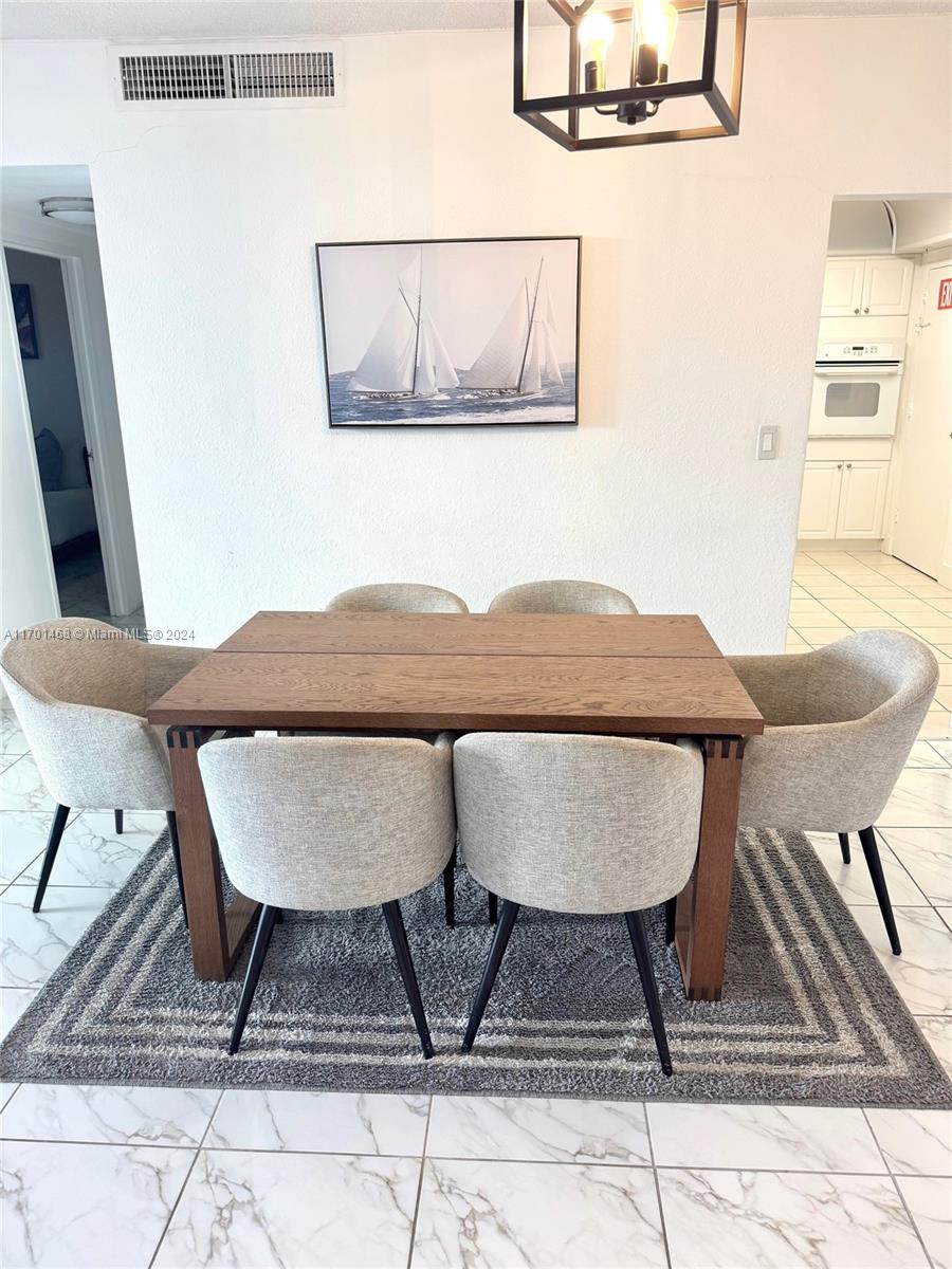 A dining area features a wooden table, six upholstered chairs, and a sailboat wall art piece — 3901 S Ocean Dr # 3Y, Hollywood FL 33019, HOLLYWOOD, FL