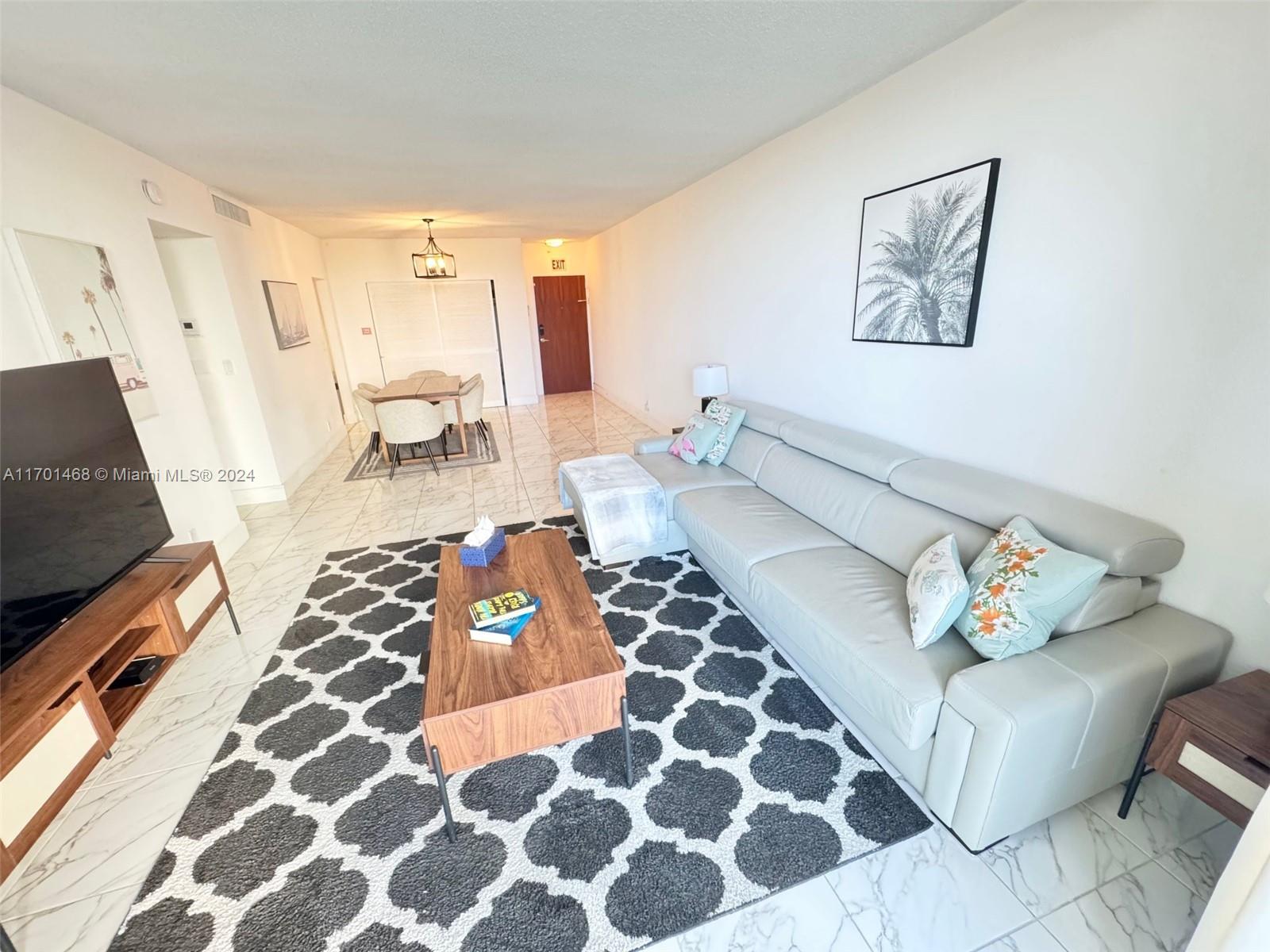 A living room features a grey sectional sofa, a patterned rug, and a dining area — 3901 S Ocean Dr # 3Y, Hollywood FL 33019, HOLLYWOOD, FL