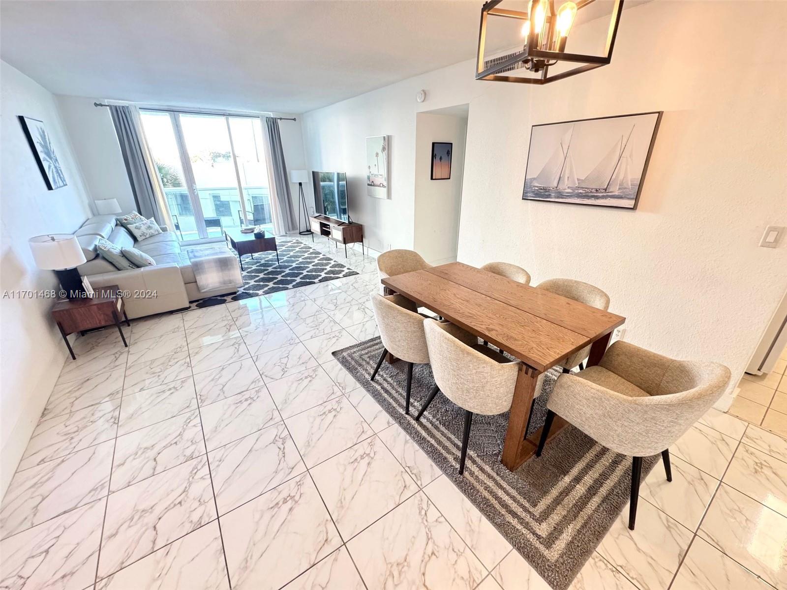 A dining area and living room feature marble-look tile floors and a wooden dining table — 3901 S Ocean Dr # 3Y, Hollywood FL 33019, HOLLYWOOD, FL