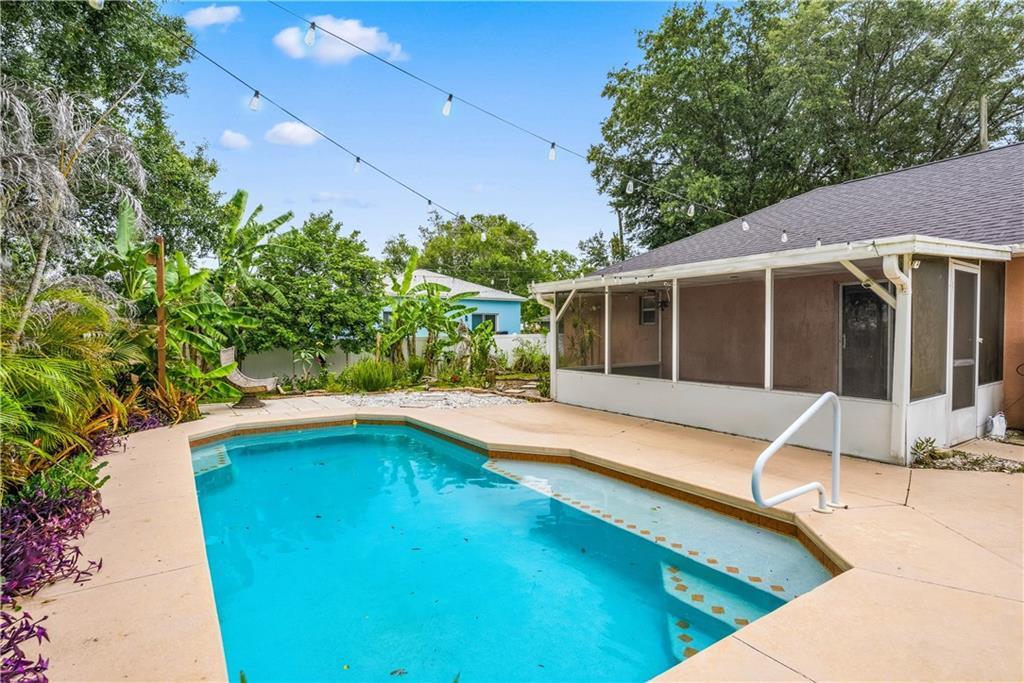 A backyard features a swimming pool, a screened-in patio, and string lights overhead — VERO BEACH, FL