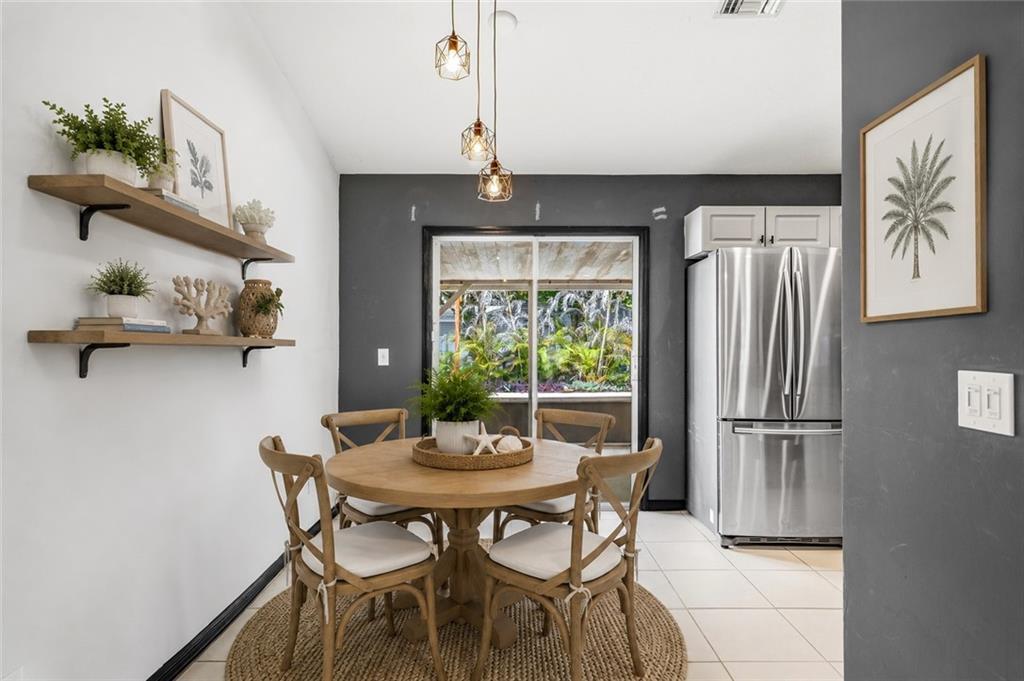 A dining area features a round wooden table, four chairs, floating shelves, and a sliding door — VERO BEACH, FL