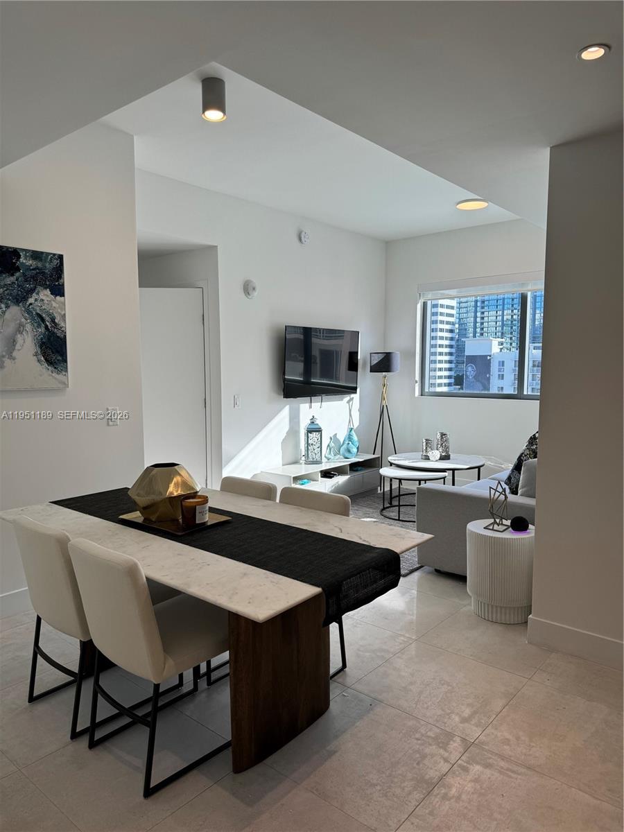 A modern living and dining area features white tile floors, a marble table, and city views — 239 SW 9th St # 1405, Miami FL 33130, MIAMI, FL