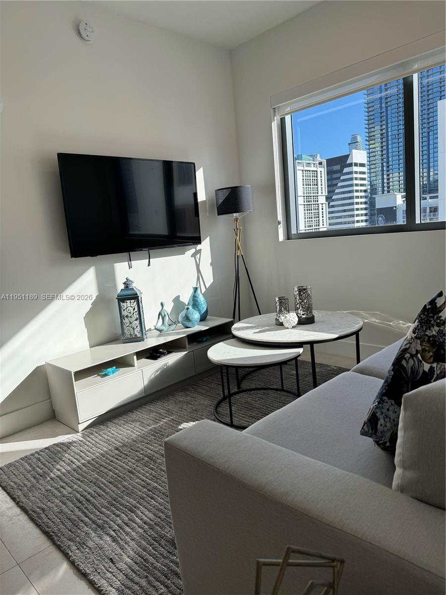 A living room features a wall-mounted television, a low media console, and nesting coffee tables — 239 SW 9th St # 1405, Miami FL 33130, MIAMI, FL