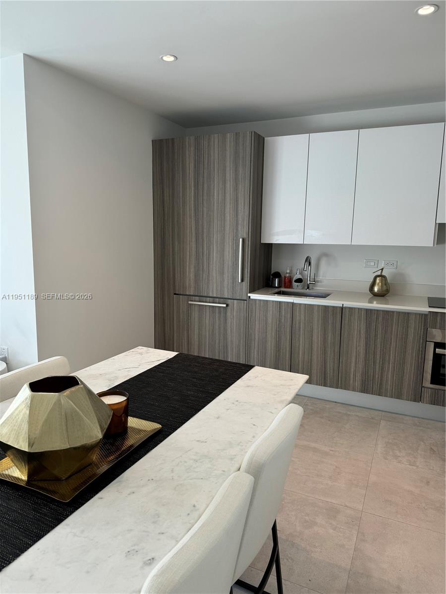 A modern kitchen features wood-grain cabinetry, white upper cabinets, and a marble-topped dining table — 239 SW 9th St # 1405, Miami FL 33130, MIAMI, FL