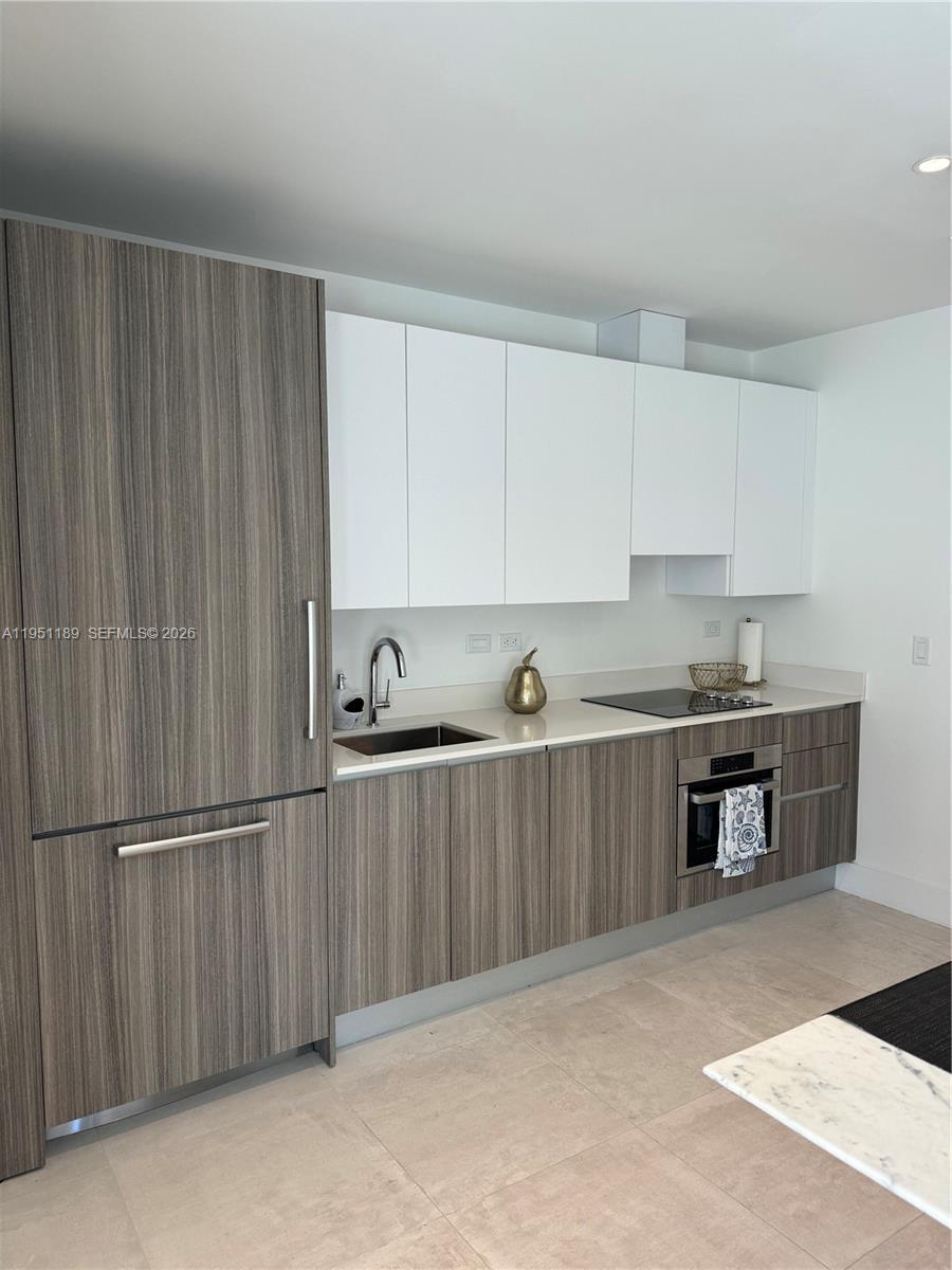 A modern kitchen features wood-grain cabinetry, white upper cabinets, and stainless steel appliances — 239 SW 9th St # 1405, Miami FL 33130, MIAMI, FL