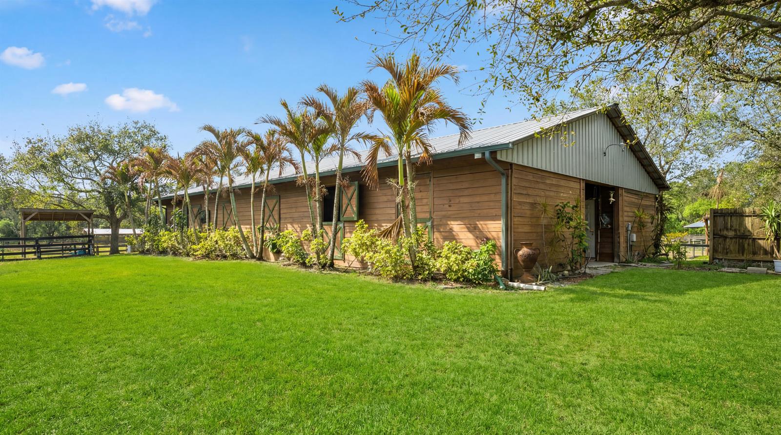 A wooden barn with a metal roof sits on a grassy lawn with palm trees — 12440 Tangerine Boulevard, FL 33412, FL