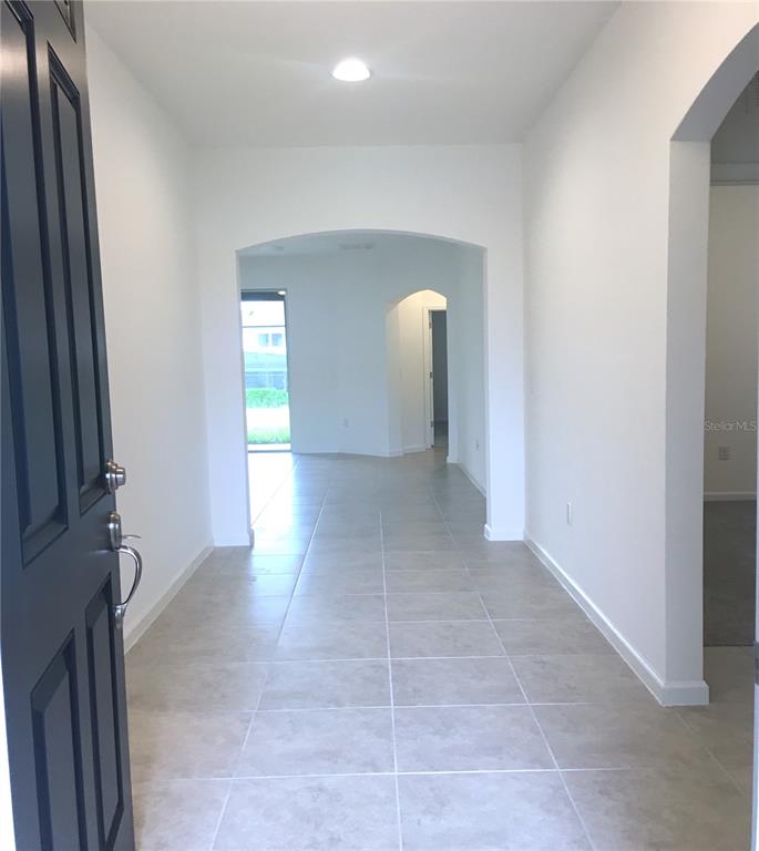 A tiled entryway leads through an arched doorway into a bright, open-concept living space — 129 BELLA VERANO WAY, DAVENPORT, FL