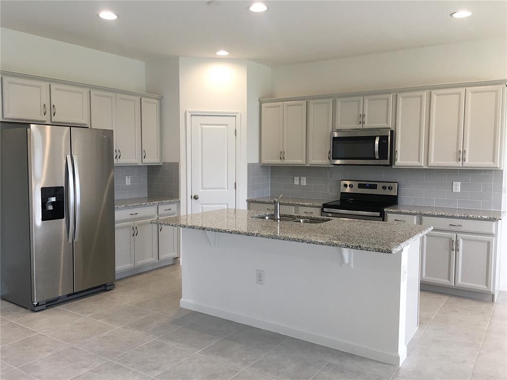 A kitchen with light gray cabinets, granite countertops, stainless steel appliances, and a central island — 129 BELLA VERANO WAY, DAVENPORT, FL