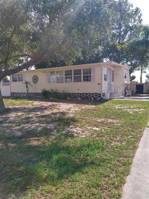 A single-story mobile home with light siding, a metal roof, and a concrete block foundation — 2031 LULLABY DRIVE, HOLIDAY, FL