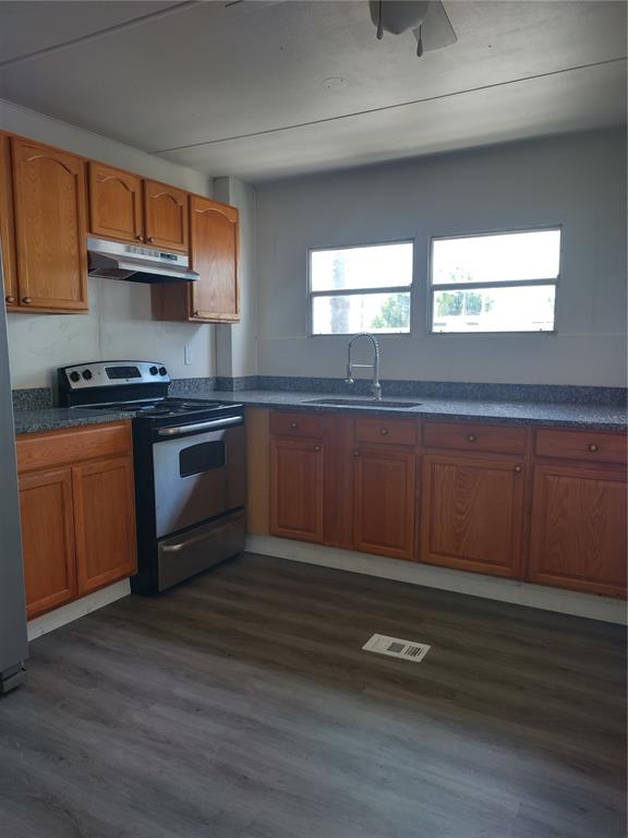 A kitchen features wood cabinets, stainless steel appliances, a gray countertop, and wood-look flooring — 2031 LULLABY DRIVE, HOLIDAY, FL