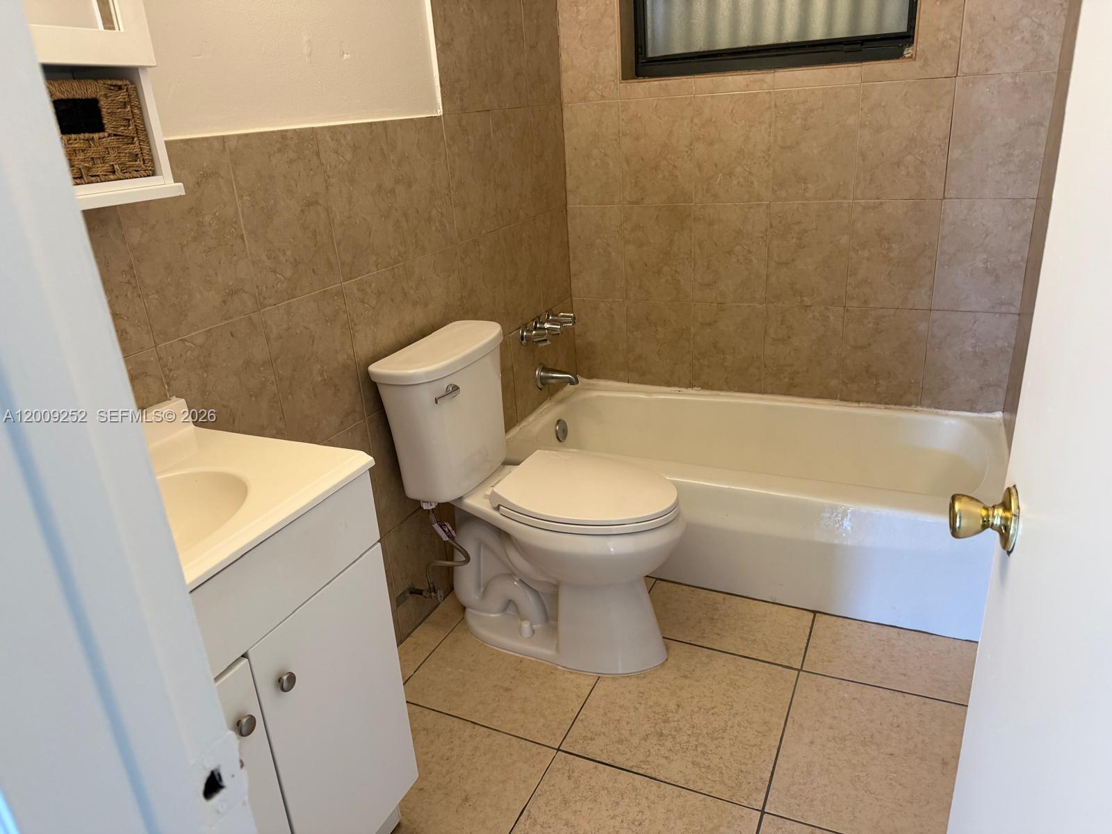 A bathroom features a white vanity, a toilet, and a bathtub with tan tiled walls — 728 SW 7th St # 2, Hallandale Beach FL 33009, HALLANDALE BEACH, FL