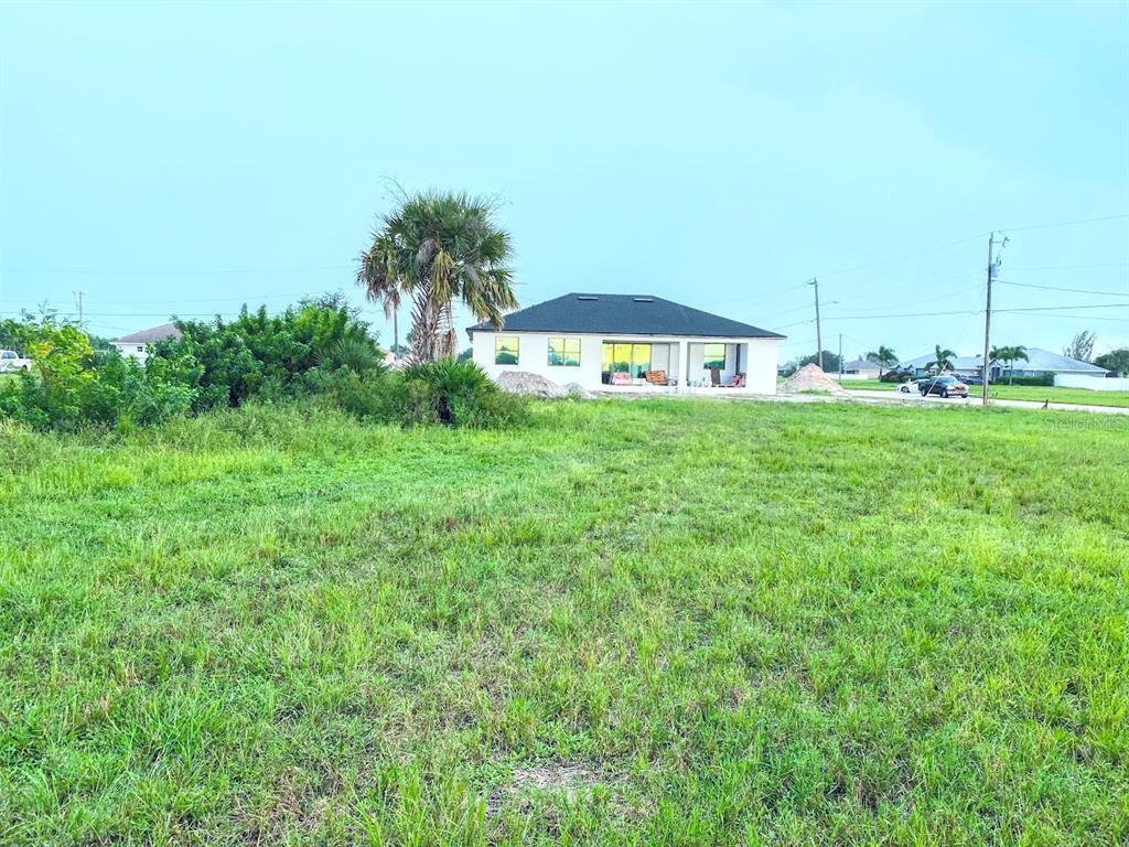 A grassy vacant lot sits in front of a newly constructed single-story house — 809 NW 29TH AVE, CAPE CORAL, FL