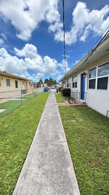 A concrete sidewalk runs between two residential buildings with green lawns and a chain-link fence — 3085 W Flagler St # 3, Miami FL 33135, MIAMI, FL