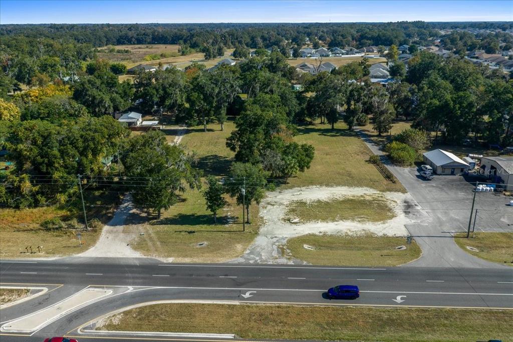 An aerial view shows a vacant, grassy lot situated next to a road and trees — 1350 NW 47TH STREET, OCALA, FL