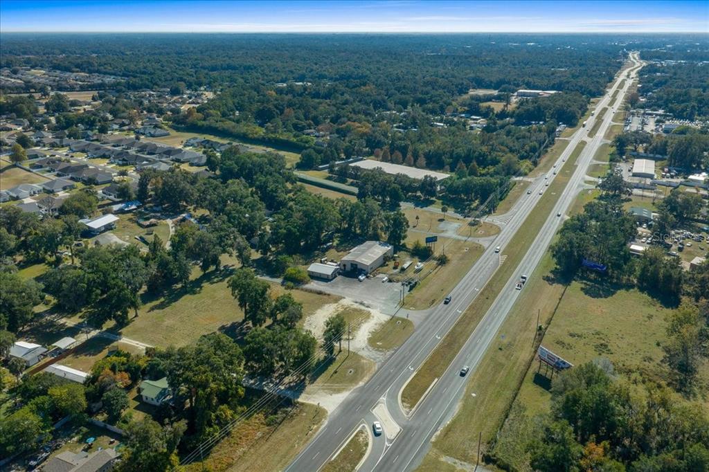 An aerial view shows a commercial building situated beside a multi-lane highway near residential neighborhoods — 1350 NW 47TH STREET, OCALA, FL