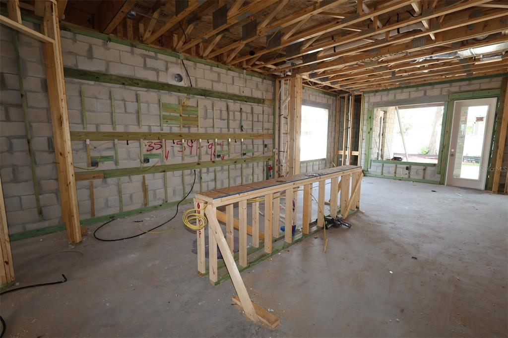 An unfinished room with drywall walls and ceiling, a kitchen island base, and large windows — 1002 W OHIO AVENUE, TAMPA, FL