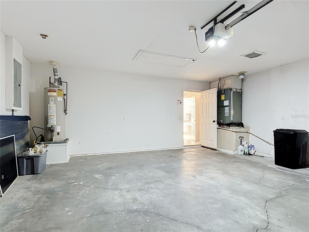 A garage with a concrete floor, water heater, HVAC unit, and an interior access door — 957 VIA BIANCA DRIVE, DAVENPORT, FL