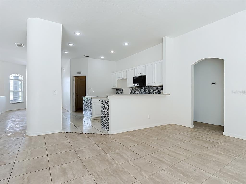 An open-concept kitchen features white cabinets, a tiled backsplash, and a breakfast bar — 957 VIA BIANCA DRIVE, DAVENPORT, FL