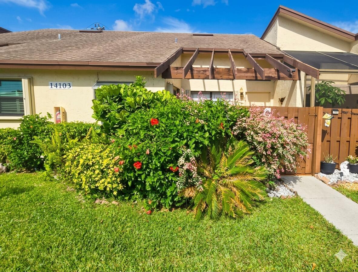 A single-story house exterior features a wooden pergola, a large hibiscus bush, and a wooden fence — 14103 Nesting Way # C, Delray Beach FL 33484, DELRAY BEACH, FL