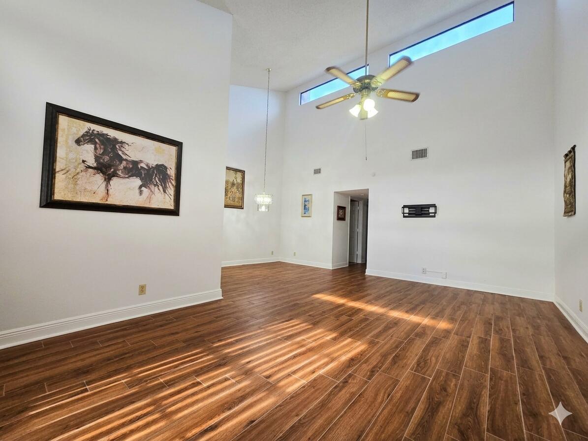 A spacious living room features high ceilings, wood-look tile floors, and a ceiling fan — 14103 Nesting Way # C, Delray Beach FL 33484, DELRAY BEACH, FL