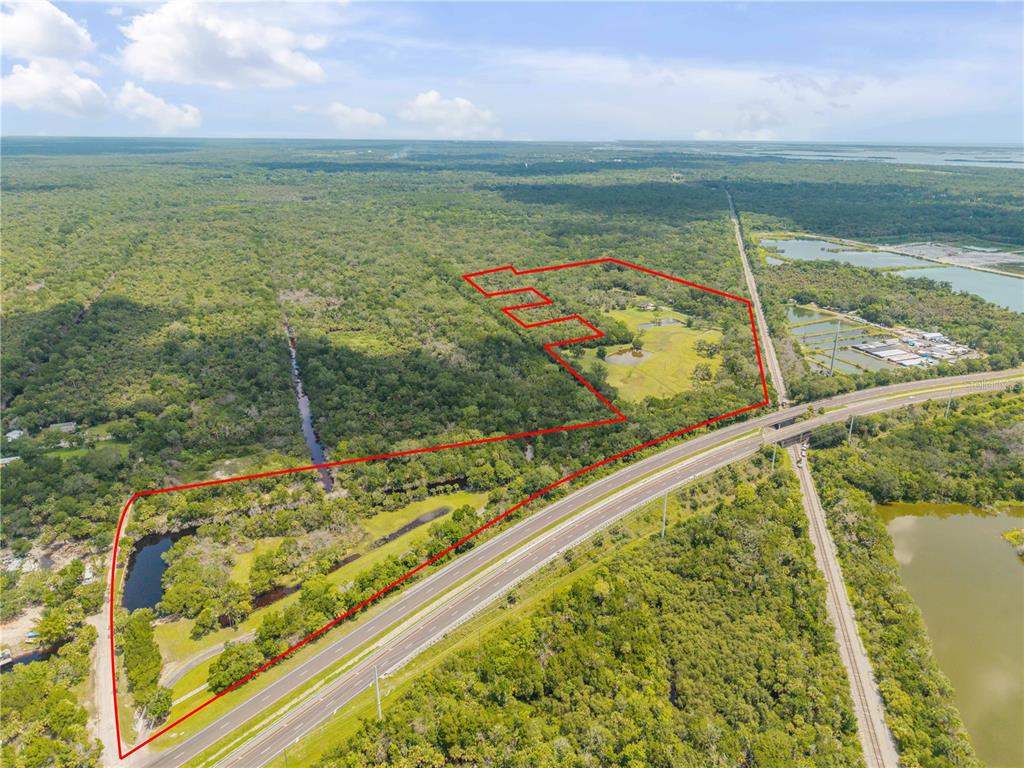 An aerial view shows a large, irregularly shaped plot of land outlined in red — 800 HIDDEN OAKS LANE, OAK HILL, FL