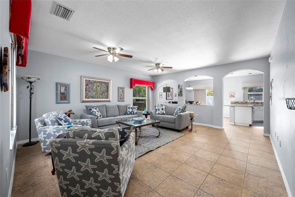 A living room with gray walls, tile flooring, two ceiling fans, and gray upholstered furniture — 7020 49TH PLACE E, PALMETTO, FL