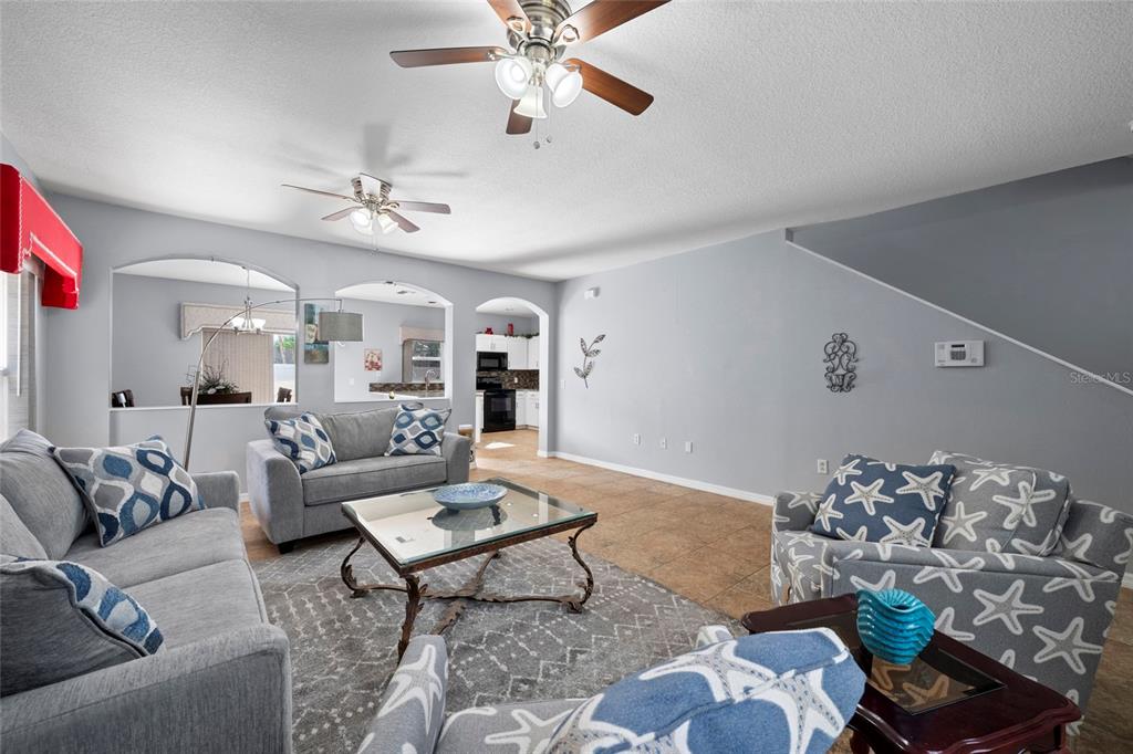 A living room with gray walls, two ceiling fans, and furniture featuring blue starfish patterns — 7020 49TH PLACE E, PALMETTO, FL