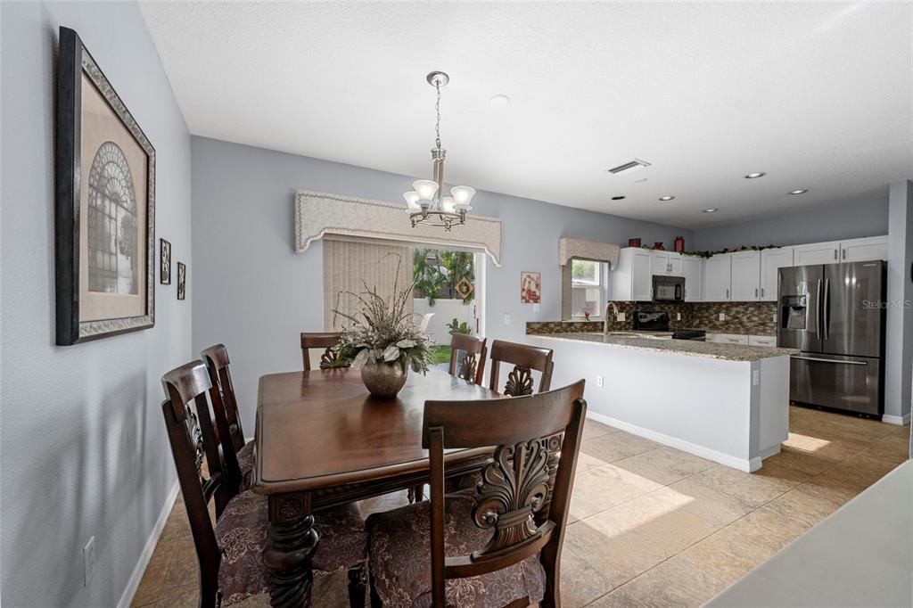 A dining area with a wooden table and chairs sits adjacent to an open kitchen — 7020 49TH PLACE E, PALMETTO, FL