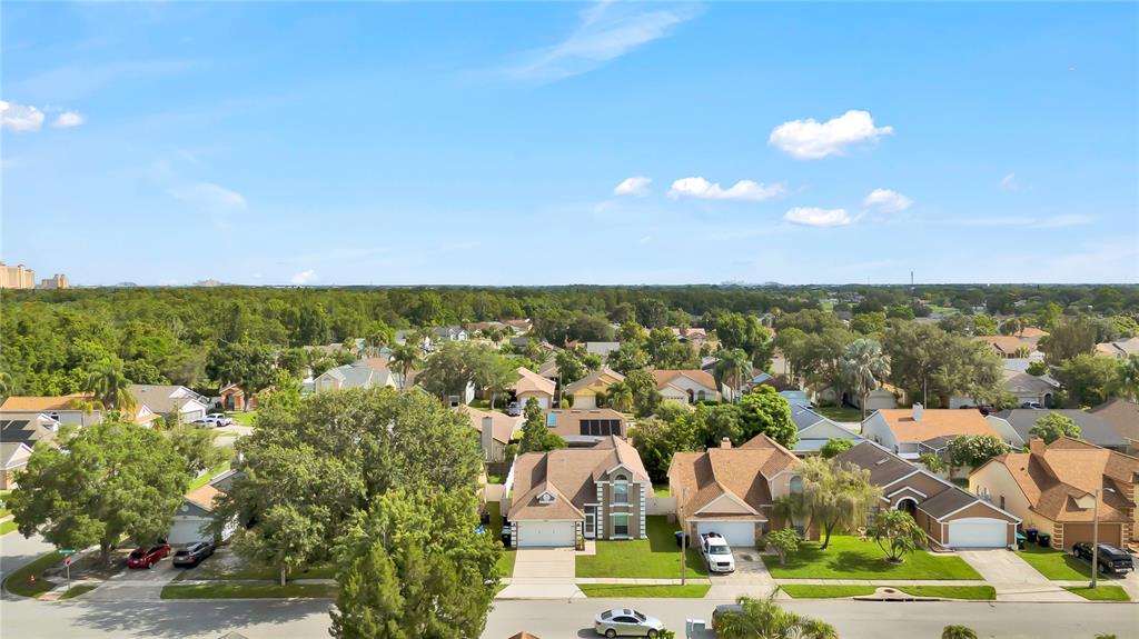 An aerial view shows a suburban neighborhood with houses, green trees, and a blue sky — 2235 MEADOWMOUSE STREET, ORLANDO, FL