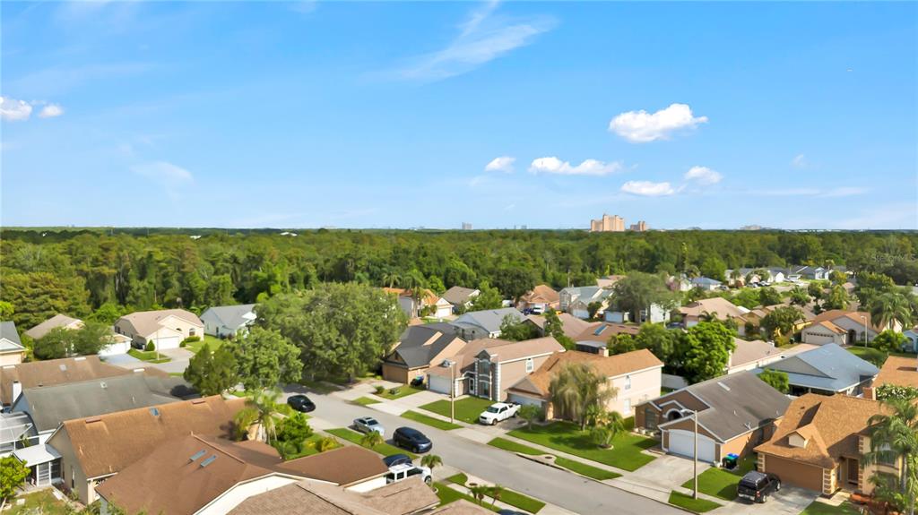 An aerial view shows a suburban neighborhood with houses, streets, and a distant treeline — 2235 MEADOWMOUSE STREET, ORLANDO, FL