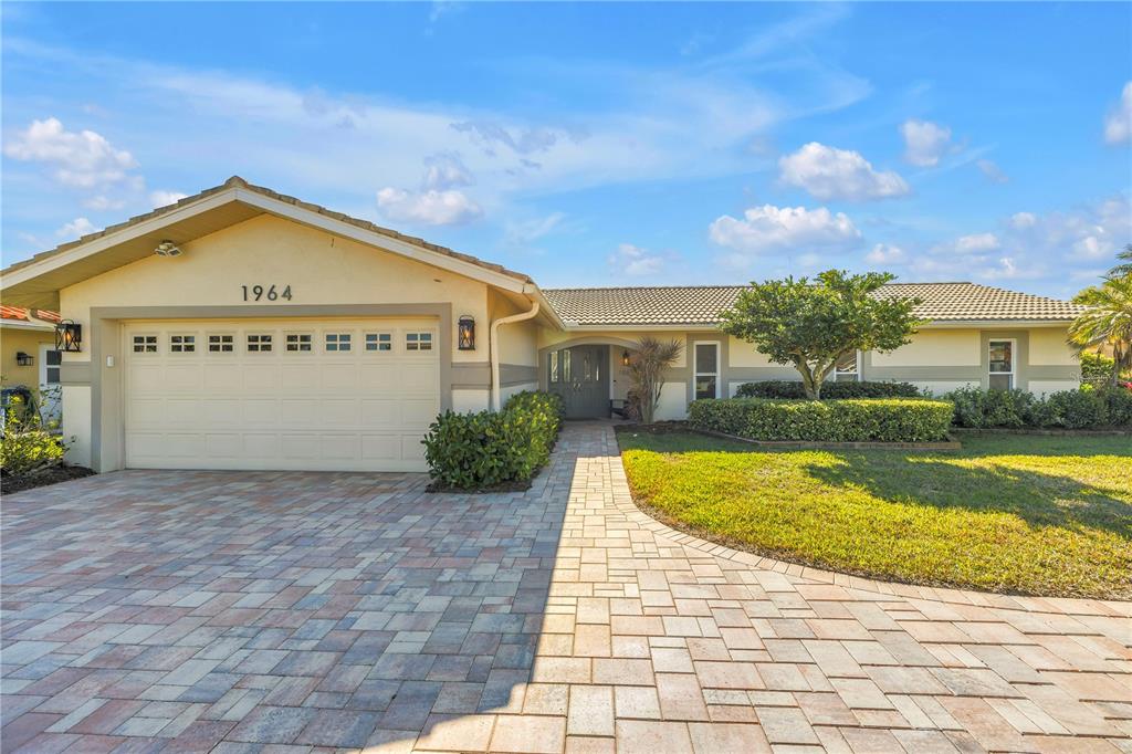 A single-story house with a paved driveway, a two-car garage, and a landscaped front yard — 1964 MASSACHUSETTS AVENUE NE, ST PETERSBURG, FL