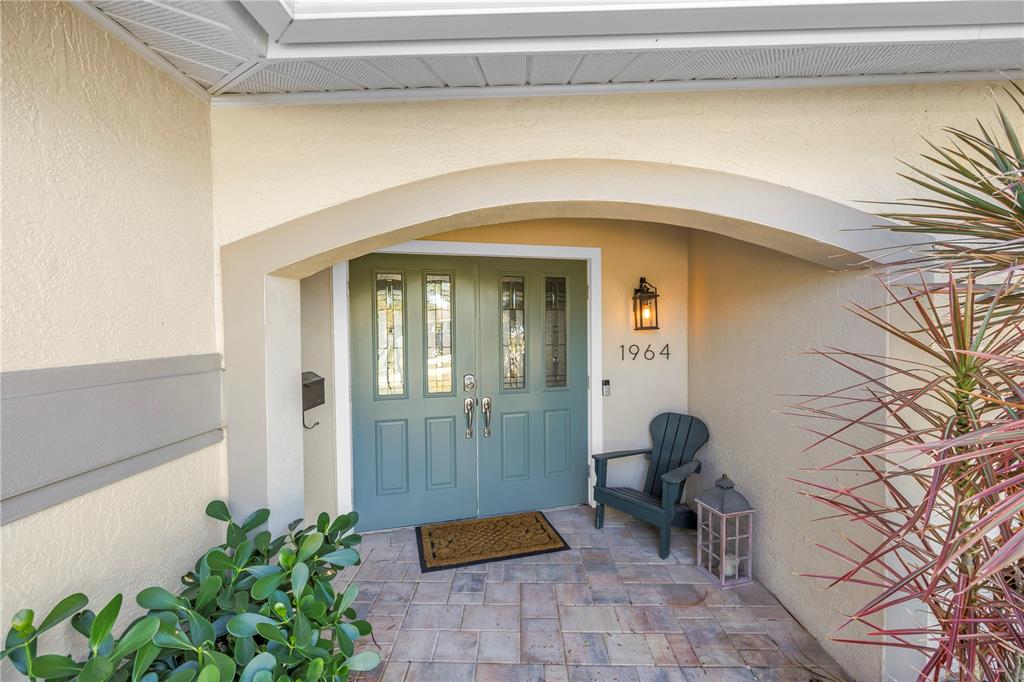 A teal double front door sits under an arched entryway with a small wooden chair — 1964 MASSACHUSETTS AVENUE NE, ST PETERSBURG, FL