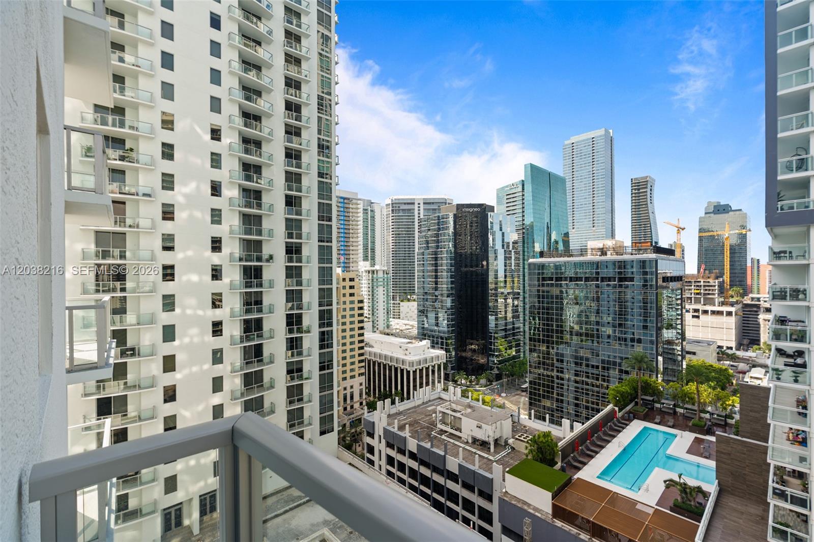 A high-rise balcony view overlooks a city skyline, surrounding skyscrapers, and a rooftop swimming pool — 1050 Brickell Ave # 2112, Miami FL 33131, MIAMI, FL