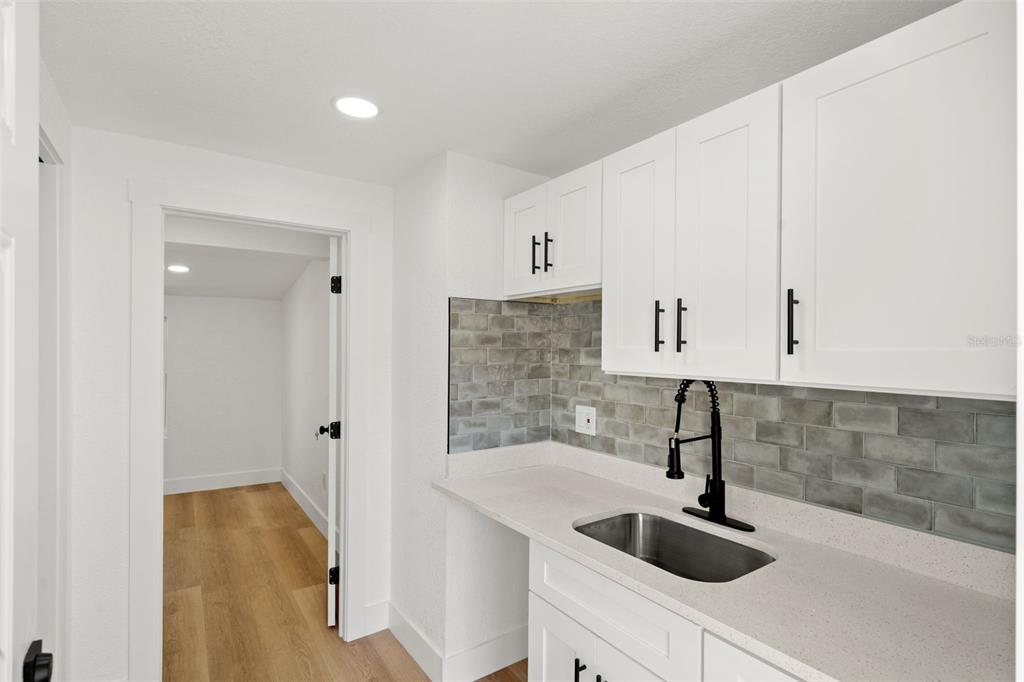 A kitchen area features white cabinets, a stainless steel sink, and a gray tiled backsplash — 2008 OAKWOOD AVENUE UNIT B, TAMPA, FL